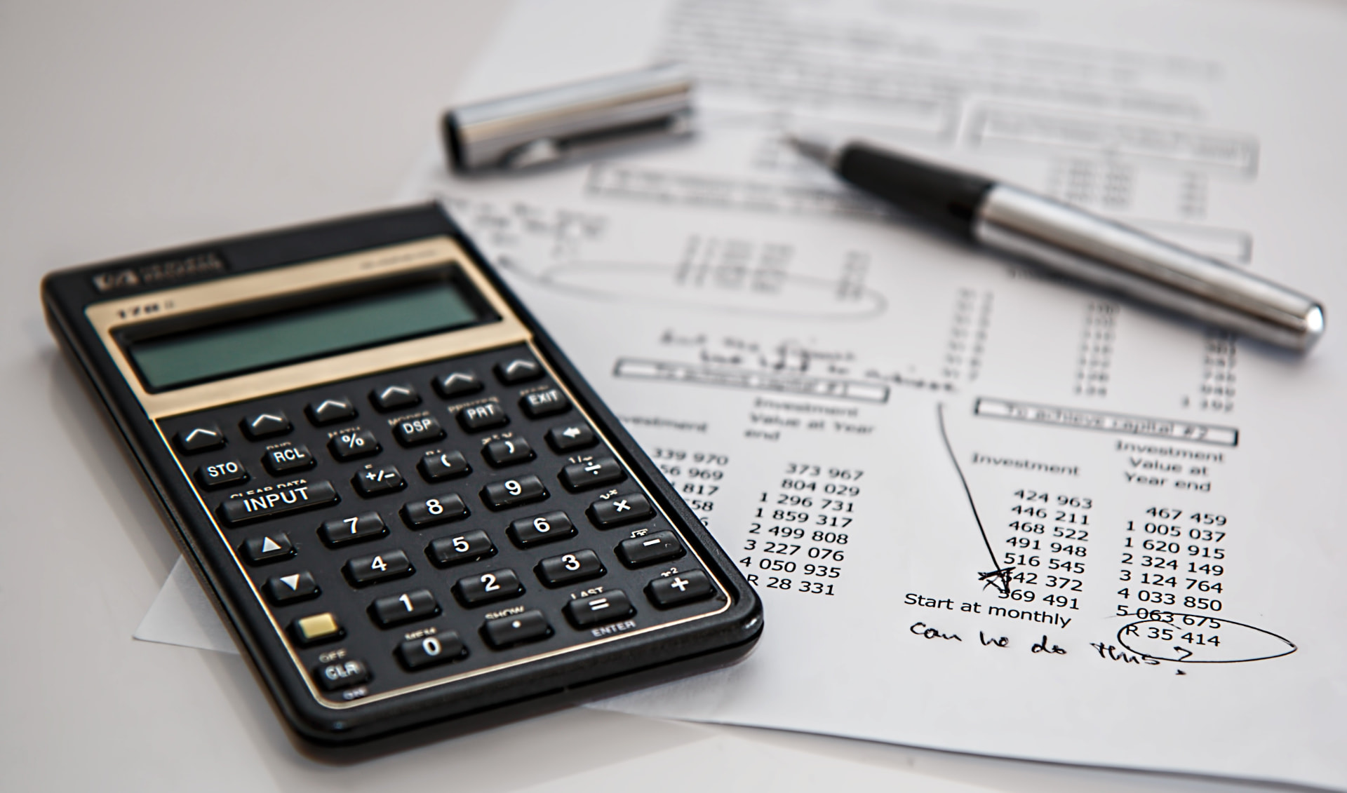 Calculator resting on printed financial statements with handwritten notes